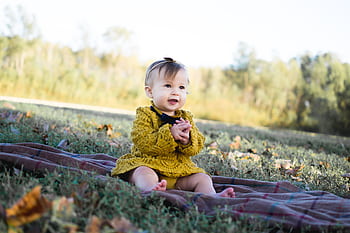 Cute baby girl sitting on a blanket in a park during fall, smiling happily. HD wallpaper