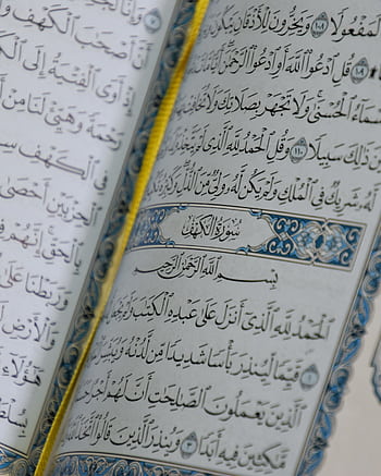 Close-up of an open Quran showing Arabic script and intricate designs, symbolizing Islamic faith. HD phone wallpaper