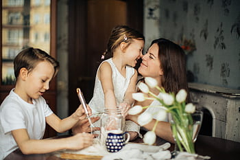 A joyful moment of a mother baking with her children in a cozy home environment. HD wallpaper