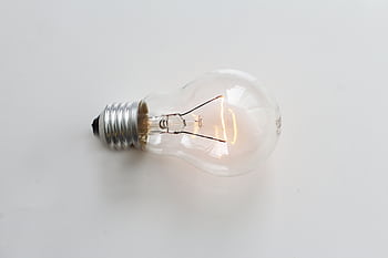 A close-up of an illuminated incandescent light bulb against a white background. HD wallpaper