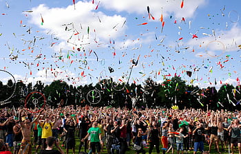A lively crowd enjoying a colorful juggling event outdoors. Perfect for summer festival themes. HD wallpaper
