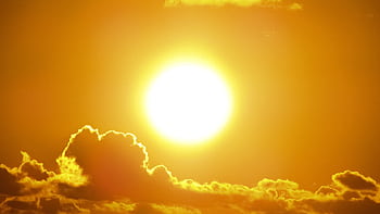 A stunning view of the golden sun shining through clouds at sunset, casting a warm glow. HD wallpaper