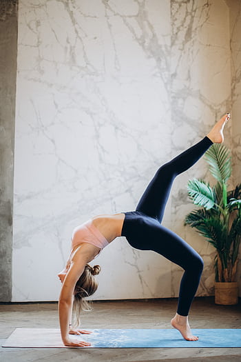 Woman practicing yoga pose indoors, emphasizing balance and flexibility. HD phone wallpaper