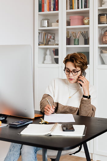 Focused businesswoman in modern office multitasking efficiently while on a call. HD phone wallpaper