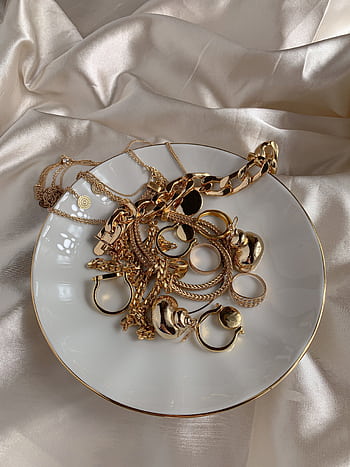 Stylish gold rings and necklaces elegantly displayed on a saucer with a silk background. HD phone wallpaper