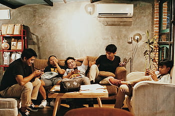 Five young men relaxing indoors, chatting and using s in a Jakarta café. HD wallpaper