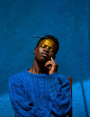 Dramatic portrait of a man against a rich blue background, exuding introspection and style. HD phone wallpaper