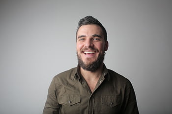 Portrait of a bearded man smiling joyfully in a casual studio setting. HD wallpaper