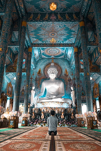 A serene view of a person worshipping inside the ornate Blue Temple of Chiang Rai, Thailand. HD phone wallpaper