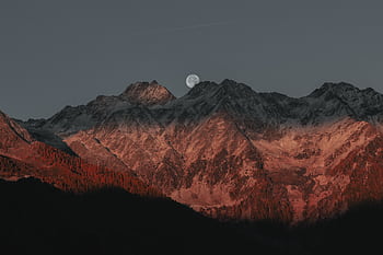 Stunning view of mountain peaks under moonlight with a twilight glow creating a dramatic landscape. HD wallpaper