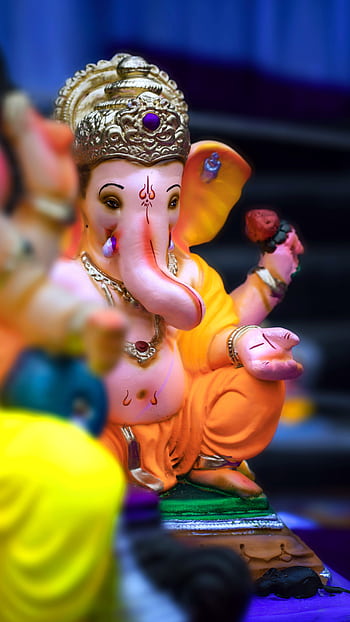Close-up of a vibrant Ganesha figurine highlighting intricate details and cultural significance. HD phone wallpaper
