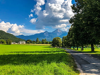 Discover the breathtaking summer scenery of Villach, Austria, featuring green fields and majestic mountains. HD wallpaper