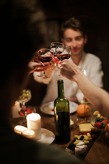 A warm and intimate dinner gathering with friends sharing wine and cheese by candlelight. HD phone wallpaper