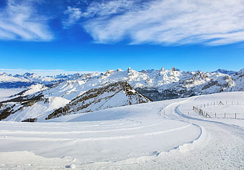 Breathtaking view of snow-covered mountains under a bright blue sky in the Swiss Alps. HD wallpaper