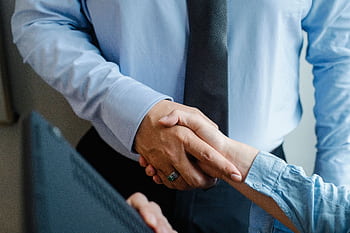 A professional handshake between two businesspeople, symbolizing collaboration and agreement. HD wallpaper