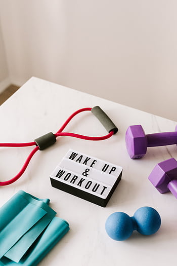 Colorful exercise equipment arranged on a light surface with a motivational sign. HD phone wallpaper