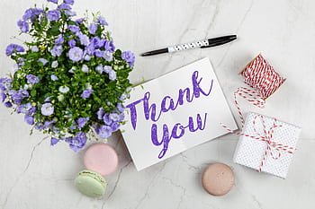 An elegant thank you card with flowers and a gift on a marble surface, perfect for expressing gratitude. HD wallpaper