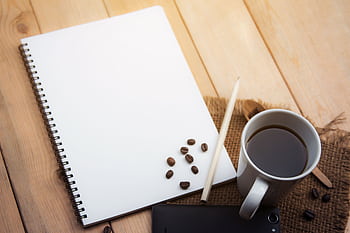 Spiral notebook, coffee cup, pencil, and smart on wooden desk, ideal for office or creative work concepts. HD wallpaper