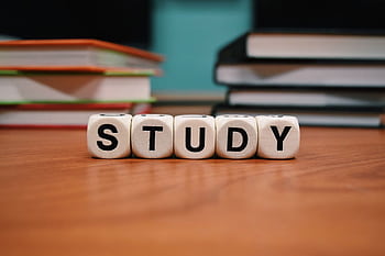 Close-up of study blocks and stacked books on a wooden desk, symbolizing education and learning. HD wallpaper