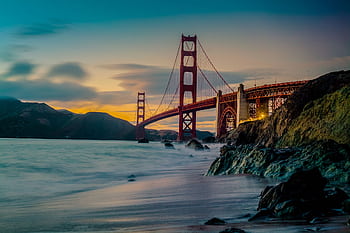 Stunning view of the Golden Gate Bridge at dusk with ocean waves and dramatic sky. HD wallpaper