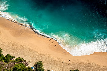 Stunning aerial view of Bali's beach with turquoise waves crashing on golden sand. HD wallpaper