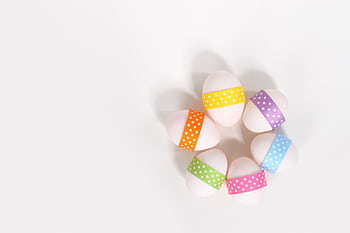 Brightly colored Easter eggs arranged in a circle with polka dot ribbons on a white background. HD wallpaper