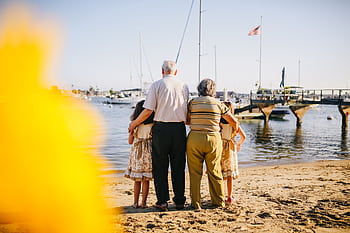 A multigenerational family enjoys a sunny day by the seaside, capturing togetherness and joy. HD wallpaper