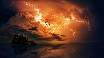 Flock of birds fly during a dramatic lightning storm over a tranquil ocean islet. HD wallpaper