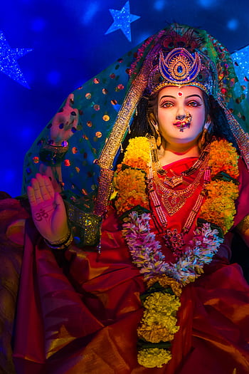 Colorful Hindu goddess statue adorned with flowers, central to Indian festival celebrations. HD phone wallpaper