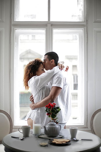 A loving couple shares an intimate moment by a window, creating a serene and romantic ambiance. HD phone wallpaper