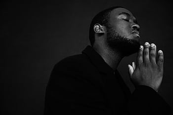 Black and white portrait of a man with clasped hands in a serene prayer pose. HD wallpaper