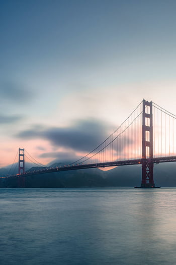 Stunning sunset view of the iconic Golden Gate Bridge in San Francisco over calm ocean waters. HD phone wallpaper