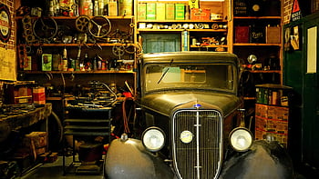 A vintage car surrounded by classic tools and equipment in a workshop setting. HD wallpaper