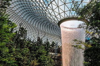 The iconic indoor waterfall at Jewel Changi Airport surrounded by lush gardens. HD wallpaper