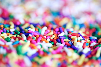 Close-up of vibrant multicolor candy sprinkles creating a playful and sugary abstract background. HD wallpaper
