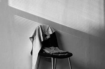 A monochrome showcasing a chair draped with clothing under dramatic light and shadow. HD wallpaper
