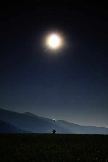 A person stands silhouetted against a moonlit night, stargazing in Brixen, Italy. HD phone wallpaper