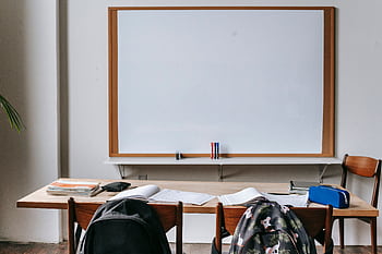 Empty classroom with wooden desks, chairs, and a large whiteboard. Ideal for educational themes. HD wallpaper