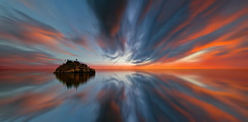 A tranquil island reflects on calm waters at sunset, creating a surreal and magical scene. HD wallpaper