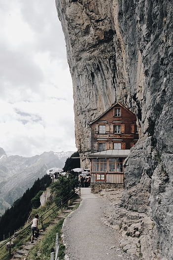 Discover the awe-inspiring cliffside Gasthaus at Ebenalp, nestled in the Swiss Alps' stunning rock formations. HD phone wallpaper