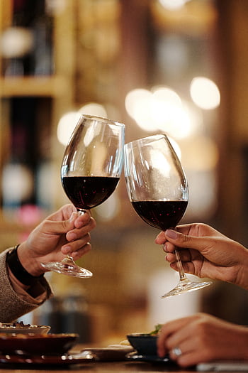 Close-up of two people toasting red wine glasses in a restaurant setting. HD phone wallpaper
