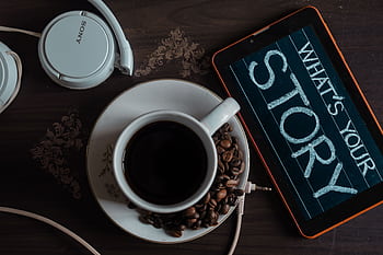 Flat lay of coffee cup, heads, and tablet with 'What's Your Story' on screen. HD wallpaper