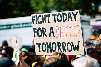 Crowd holding a protest sign with 'Fight Today for a Better Tomorrow', outdoors and during the day. HD wallpaper