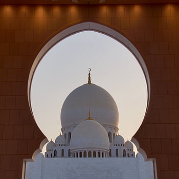A captivating view of the Sheikh Zayed Grand Mosque's dome framed by an ornate arch in Abu Dhabi. HD wallpaper