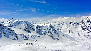A breathtaking view of snow-covered alpine mountains under a clear blue sky, ideal for winter sports. HD wallpaper