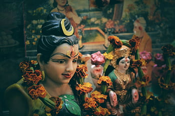 Close-up of Hindu deity statues adorned with marigold flowers in a vibrant cultural setting. HD wallpaper