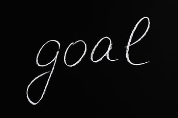 Elegant handwritten 'goal' on a black chalkboard background conveying ambition and purpose. HD wallpaper