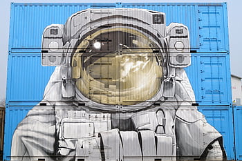 Astronaut mural painted on blue shipping containers, blending art and urban environment. HD wallpaper