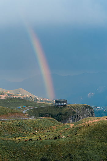 Breathtaking view of a rainbow over the lush, rolling hills of Ganisi, Georgia, creating a serene natural landscape. HD phone wallpaper