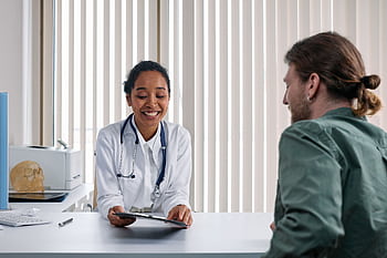 A doctor and patient engaging in a positive consultation in a bright clinic setting. HD wallpaper